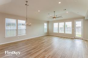 Pearland house for rent - an empty living room with wood floors and large windows