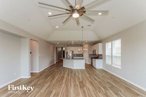 Pearland house for rent - an open kitchen and living room with wood flooring and a ceiling fan