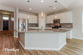 Pearland house for rent - a kitchen with white cabinets and a marble counter top