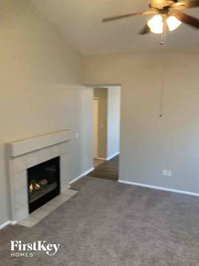 Colorado Springs house for rent - A living room with a fireplace and a ceiling fan.