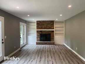 Fairfield house for rent - an empty living room with a brick fireplace and wooden floors
