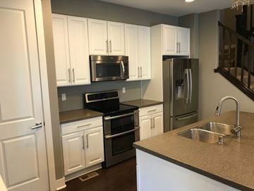 Lakewood house for rent - a kitchen with white cabinets and stainless steel appliances