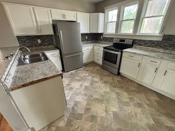 Akron house for rent - A kitchen with a granite countertop and white cabinets.
