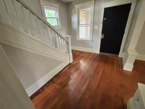 Akron house for rent - A hallway with a wooden floor and white staircase.