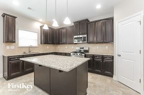 Conyers house for rent - a kitchen with dark wood cabinets and granite counter tops