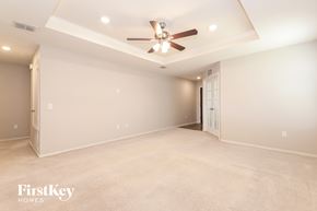Aubrey house for rent - A spacious room with a ceiling fan and beige carpeting.