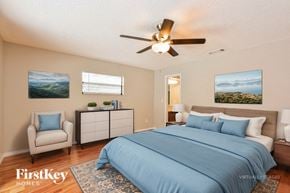 Longwood house for rent - A bedroom with a bed, chair, and two pictures on the wall.