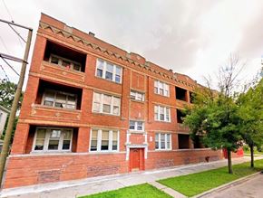 Chicago apartment for rent - A red brick building with white windows and a red door.