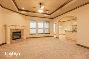 Mustang house for rent - a large living room with a fireplace and a ceiling fan