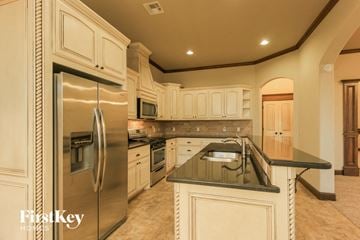 Mustang house for rent - a large kitchen with stainless steel appliances and white cabinets