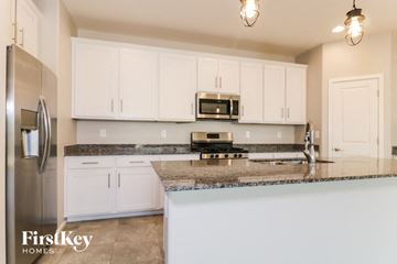Surprise house for rent - a kitchen with white cabinets and granite counter tops