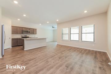 Fate house for rent - A spacious kitchen with wooden floors and a refrigerator on the left.