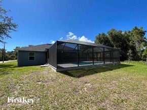 Port Charlotte house for rent - A modern house with a glass wall is situated in a grassy area.