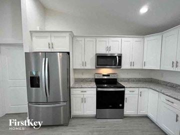 Port Charlotte house for rent - A kitchen with a stainless steel refrigerator and a black stove top oven.