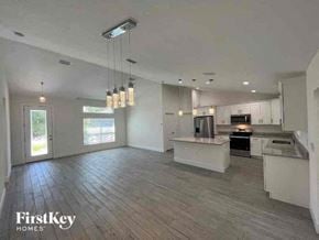 Port Charlotte house for rent - A spacious kitchen and living room with wood flooring and white walls.