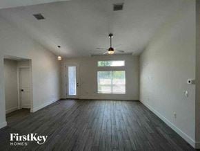 Port Charlotte house for rent - A spacious room with wooden floors and a ceiling fan.