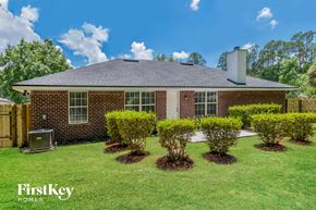 Jacksonville house for rent - A house with a brick exterior and a chimney is surrounded by bushes.