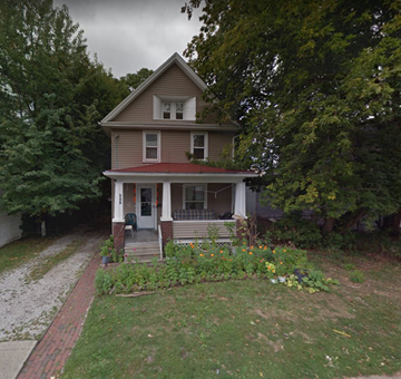 Akron house for rent - A house with a red roof and a porch with a white railing.