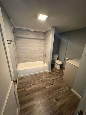 Akron house for rent - A bathroom with a white tub and wooden floors.