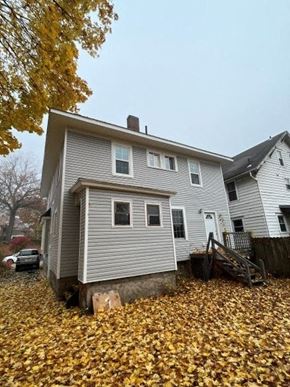 Akron apartment for rent - A house with a grey siding and a white door is surrounded by fallen leaves.