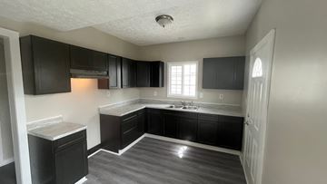 Akron apartment for rent - A kitchen with black cabinets and a white door.