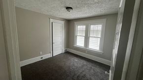 Akron apartment for rent - A room with a carpeted floor, a door, and a window with white blinds.