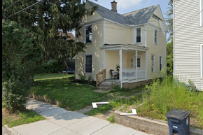 Akron house for rent - A house with a front porch and a trash can in front of it.