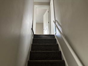 Akron house for rent - A staircase with a carpeted runner and white walls.