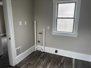 Akron house for rent - A room with a window, a white door, and a white pipe on the wall.
