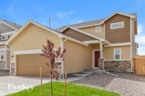 Colorado Springs house for rent - a beige house with a garage and a tree in the driveway