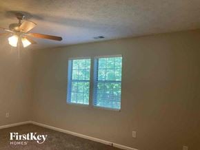 Gainesville house for rent - a bedroom with a ceiling fan and a window