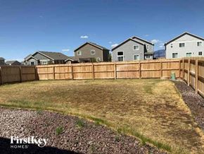 Colorado Springs house for rent - A backyard with a wooden fence and a grassy area.