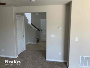 Colorado Springs house for rent - A room with a carpeted floor and a staircase in the background.