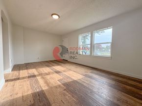 Longview apartment for rent - A room with wooden flooring and a window showing a view of a tree and a building outside.