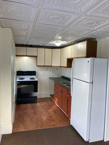 South Paris apartment for rent - A white refrigerator in a kitchen with wooden floors and cabinets.