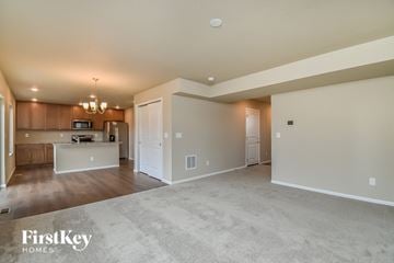 Colorado Springs house for rent - A spacious living room with a kitchen in the background and a carpeted floor.