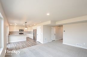 Colorado Springs house for rent - A spacious, well-lit kitchen and living room with a carpeted floor and wooden cabinets.
