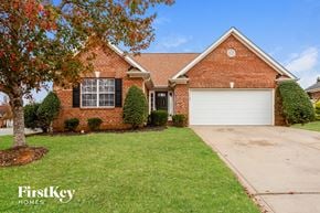 Midland house for rent - A brick house with a garage door and a tree in front.