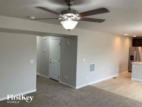Colorado Springs house for rent - an empty living room with a ceiling fan and a door
