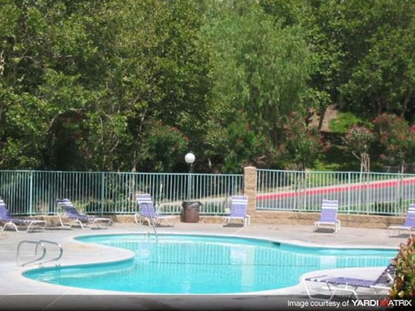 Santa Clarita apartment for rent - a swimming pool with chairs and a fence around it