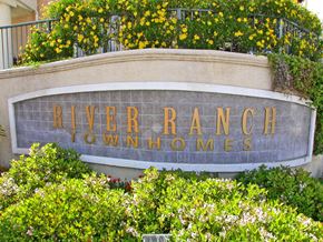 Santa Clarita apartment for rent - A sign that says River Ranch Townhomes is surrounded by greenery.