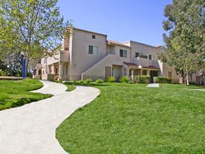 Santa Clarita apartment for rent - a sidewalk leading to a building with grass and trees