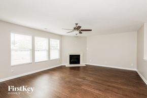Charlotte house for rent - A spacious room with a fireplace and a ceiling fan.