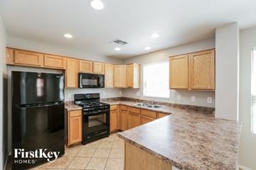 Gilbert house for rent - a kitchen with wooden cabinets and black appliances