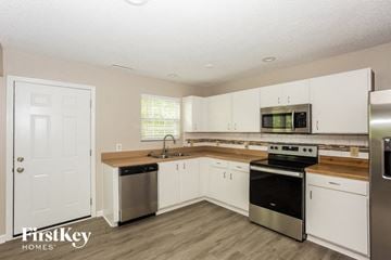 Charlotte house for rent - a kitchen with white cabinets and stainless steel appliances