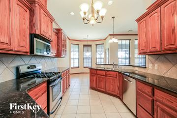 Oklahoma City house for rent - A kitchen with red cabinets and a black stove top oven.