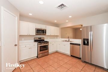Houston house for rent - A kitchen with a stove top oven, microwave, refrigerator, and sink.