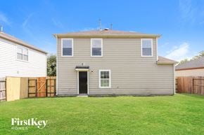 Houston house for rent - A house with a grey siding and a black door is shown with a grassy yard.