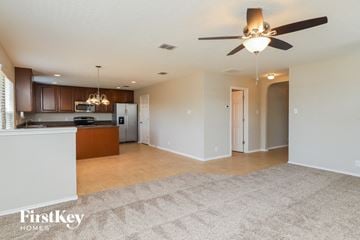 Converse house for rent - A spacious living room with a kitchen area in the background and a carpet on the floor.