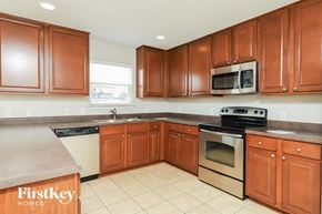Converse house for rent - A kitchen with brown cabinets and a stove top oven.